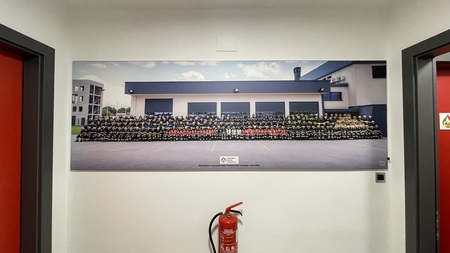 Fotografija 220 gasilcev iz vseh 18 PGD v zaščitnih oblekah, montirana pred pisarno GZ Grosuplje v GC Grosuplje ob 70-letnici GZ Grosuplje.